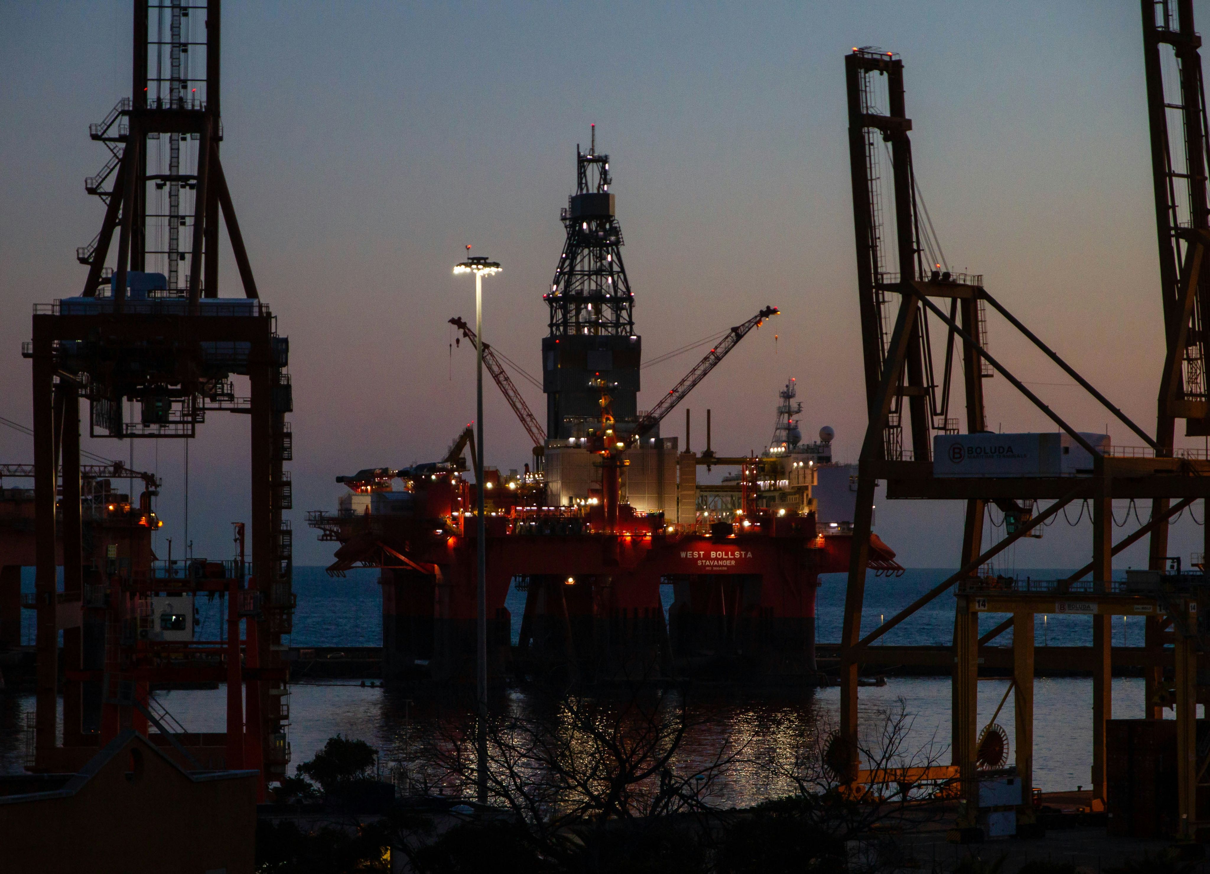 Offshore oil platform and port cranes at dusk